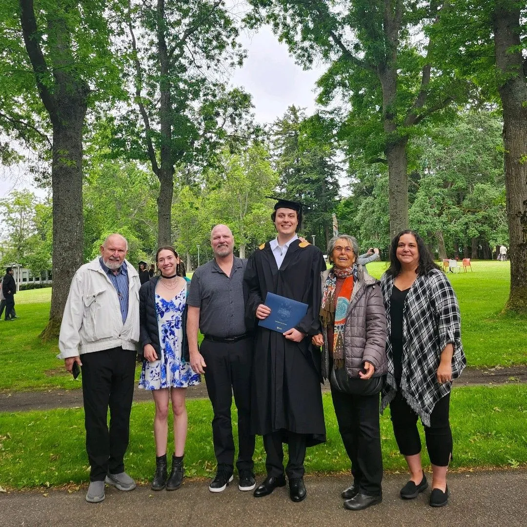 Nathan Pannell holding his degree with family after graduating from the University of Victoria